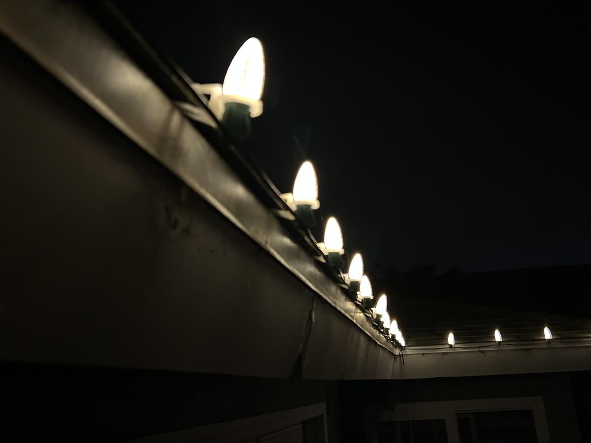 Close view of C9 bulbs clipped along a gutter at night