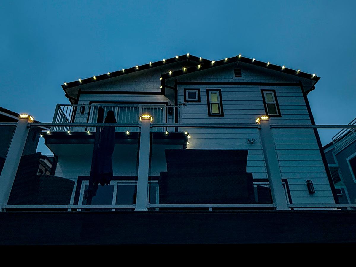 Cool white lights on a roofline and deck posts at dusk