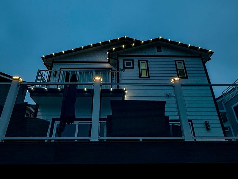Cool white lights on a roofline and deck posts at dusk