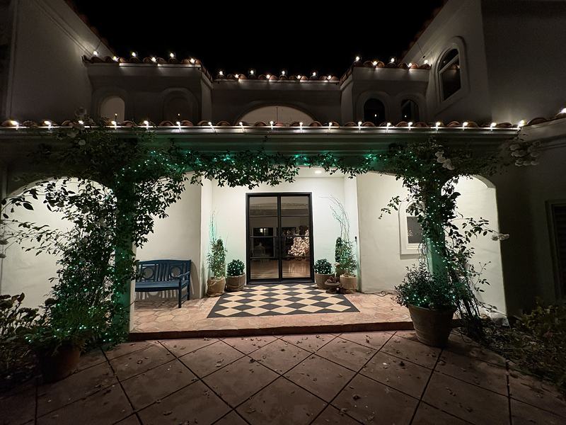 Courtyard entry with roofline lights and green mini lights on the climbing vines