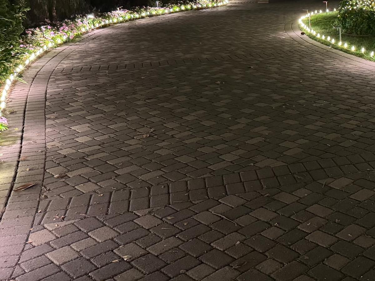 Paver driveway edged on both sides with warm white lights