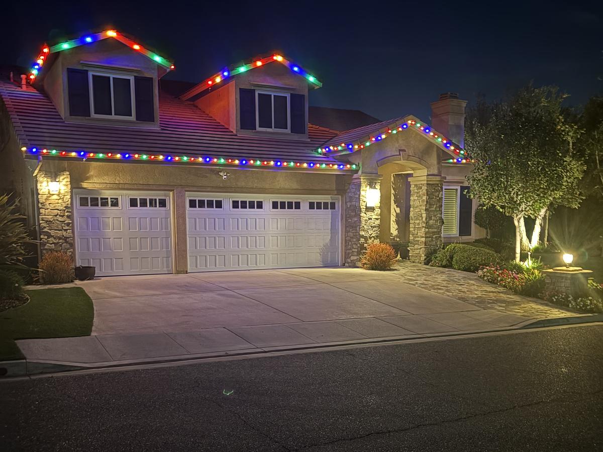 Home with multicolor lights on the dormers, roofline and entry gable