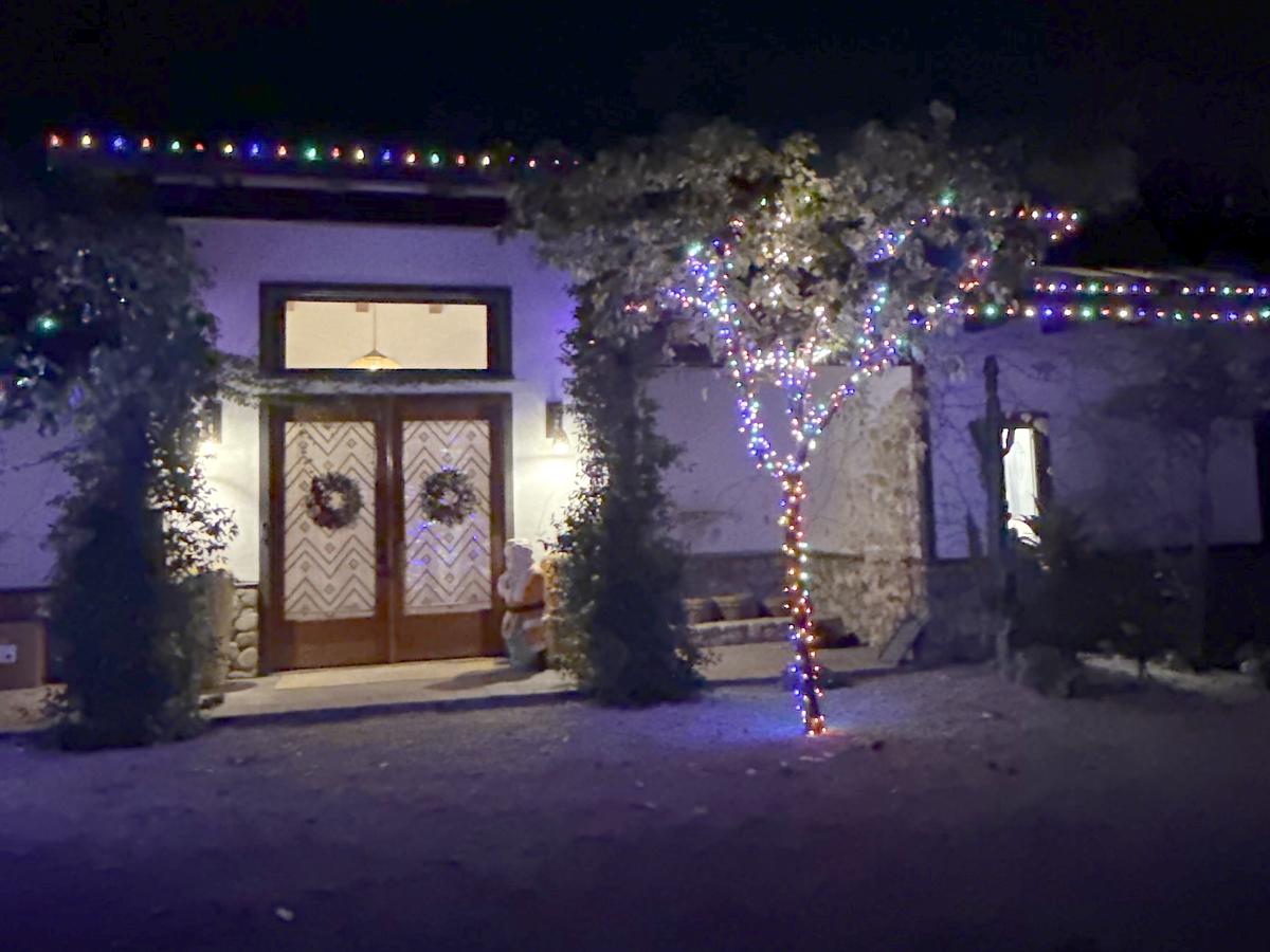 Ojai home with multicolor lights on the roofline and wrapped trees