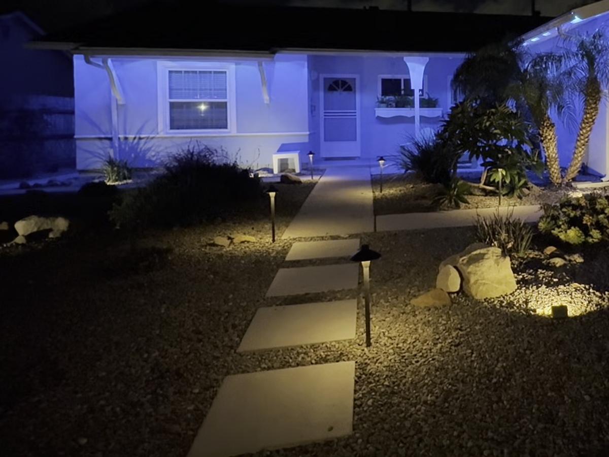Path lights along stepping stones and an accent light on boulders in a front yard