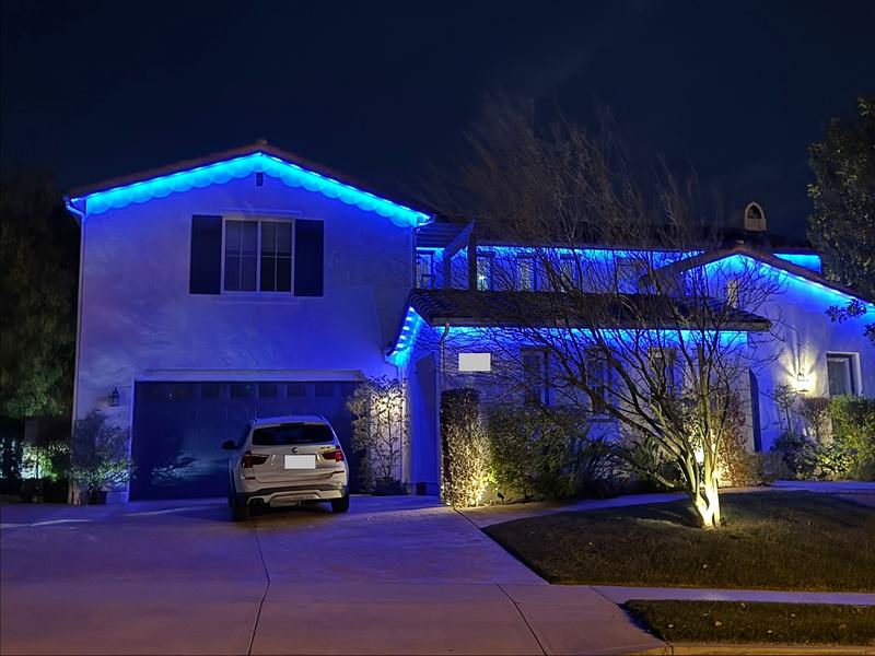 Two-story home with permanent roofline lights set to blue