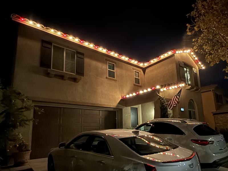 Two-story home with red and warm white lights along the roofline