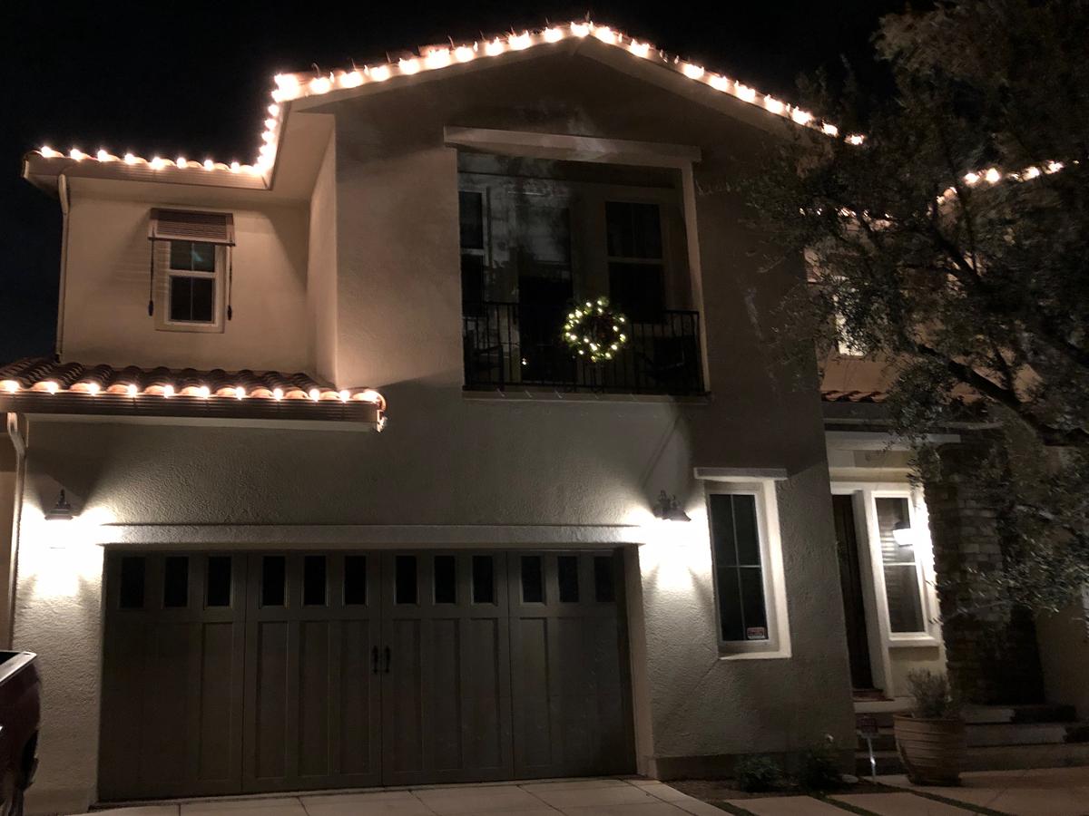 Simi Valley home with warm white roofline lights and a lit wreath on the balcony