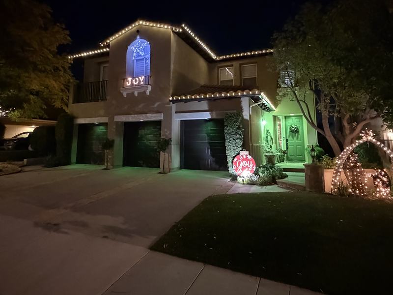 Stevenson Ranch home with warm white roofline lights, a wrapped tree and a lit arch