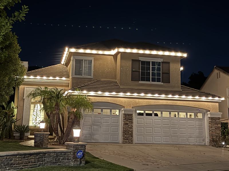 Two-story home in Thousand Oaks with warm white lights on both rooflines